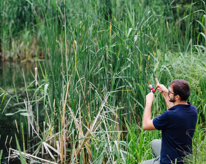 man-fishing-grassy-lake